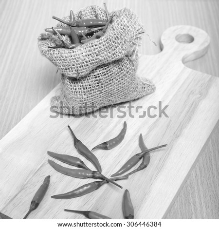 red chili peppers on cutting board over wood table background black and white tone color style