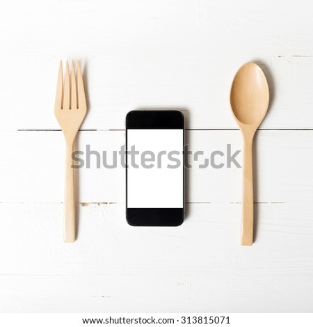 spoon and smart phone concept eating social over white table background
