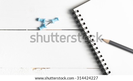 pencil and notepad with push pin over white table view from above