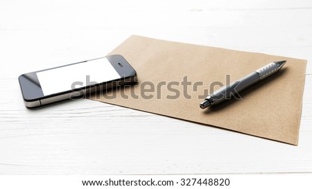 cellphone with brown paper and pen over white table