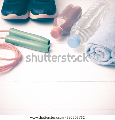 fitness equipment : running shoes,towel,jumping rope,drinking water and orange juice on white wood background vintage tone style