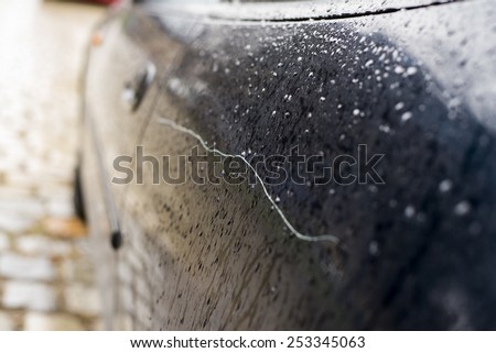 Scratched car paint with door handle and tire out of focus