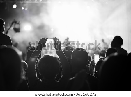Supporters recording at concert, black and white, noise
