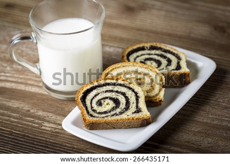 Glass of milk with poppy seed cakes on wooden background