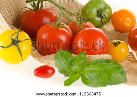 Different types of tomatoes of different colors with basket and