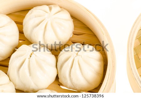 Chinese steamed buns in bamboo steamer basket isolated on white