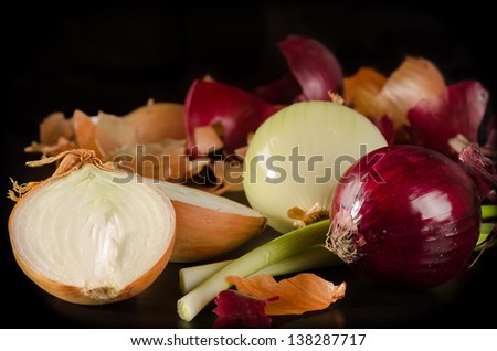 White, red and green onion with the husk on black wooden background