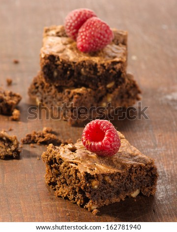 Chocolate brownies with raspberries on wooden background
