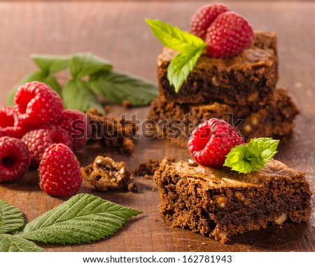 Chocolate brownies with raspberries on wooden background