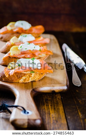 smoked salmon on toasted bread with cream fresh, lemon and chives on white plate