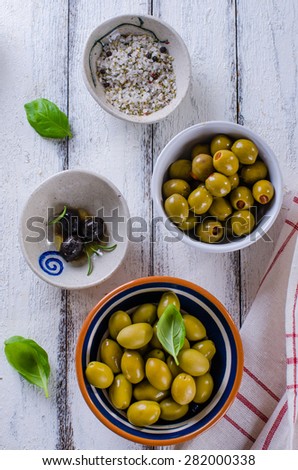 Assortment of olives with herb and sea salt on white wooden back