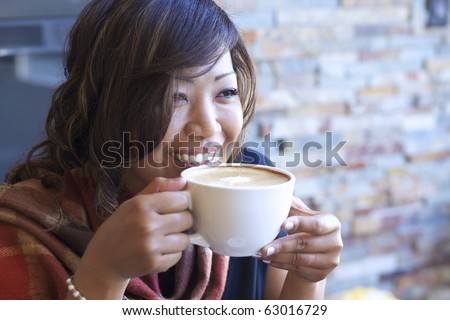 Portrait of beautiful Asian woman drinking cappuccino at a coffee shop.