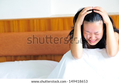 woman crying sitting on the bed clawing her head in sad