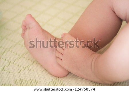 Baby little feet touch each other on mat