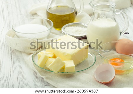 baking ingredients eggs, flour, sugar, butter, vanilla, cream on a background