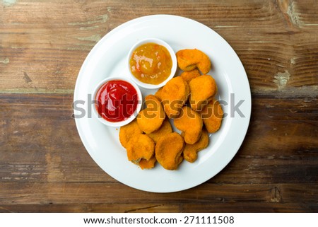 Nuggets on a plate with ketchup and sauce