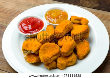 Nuggets on a plate with ketchup and sauce
