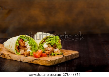 Tortilla wraps with fresh ingredients on a wooden background