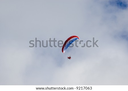 Man enjoying the ride in a blue white red paraglider