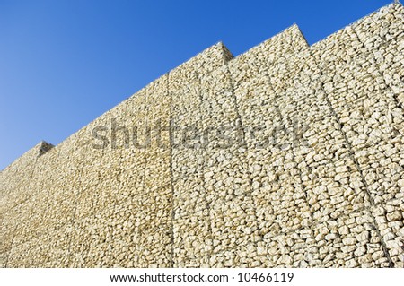 Safety wall made of stacked meshed boxes of stones