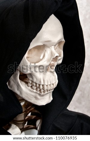 Skeleton face in a black grim reaper hood