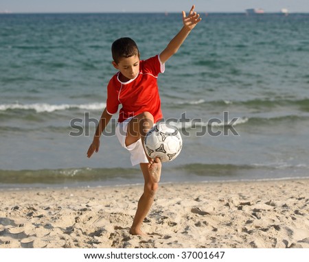 boy plays soccer on the beach