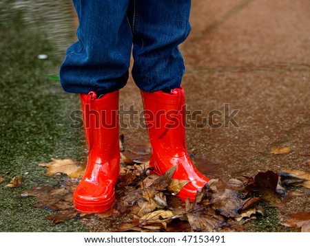 child with rain boots jumps into a puddle