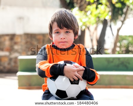 Angry boy with football soccer / shirt and ball in a park