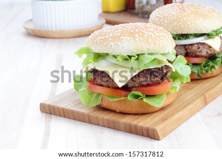 Two grilled homemade hamburgers on a wooden board in environment from the breakfast table.