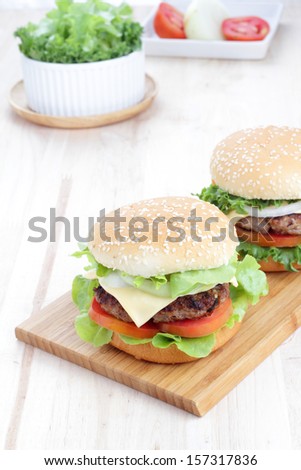 Two grilled homemade hamburgers on a wooden board in environment from the breakfast table.