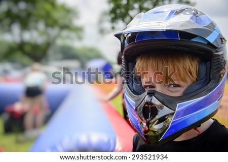Young boy wearing a motorcycle helmet. Young boy wearing motorcycle helmet, at a county fairground, waiting to go on a quad bike. Safety concept