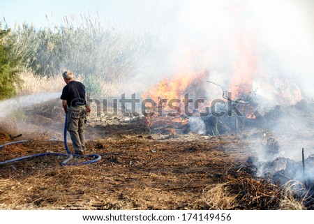 civilian man extinguishing fire with a hose