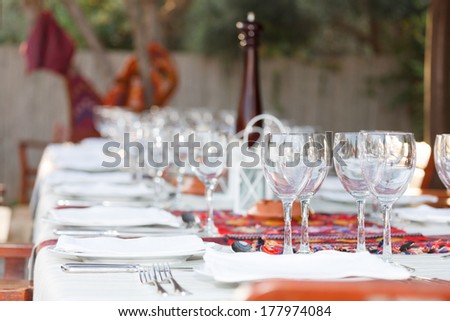Formal table setting with elegant glassware and linen at an outdoor BBQ in celebration of a special event