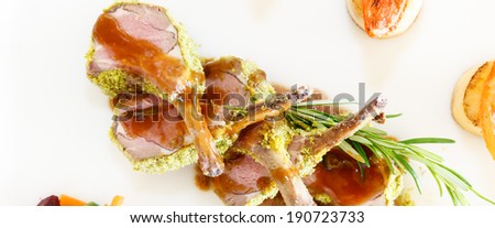 Rack of lamb cut into individual cutlets topped with a sprig of fresh rosemary and served drizzled with gravy for a gourmet dinner