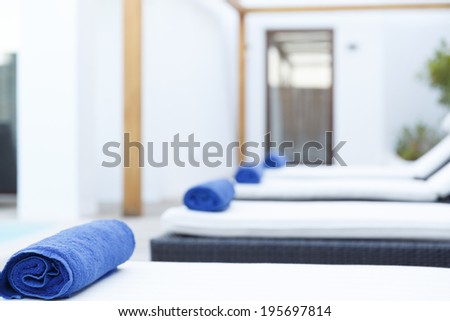 Treatment room in a resort with a row of clean white beds and couches with blue towels in a fresh white room