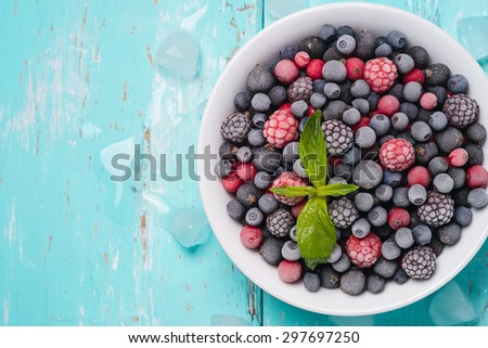 Frozen berries on a turquoise background with space for text, top view