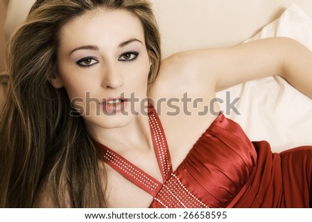 Beautiful young woman on the bed wearing a red top