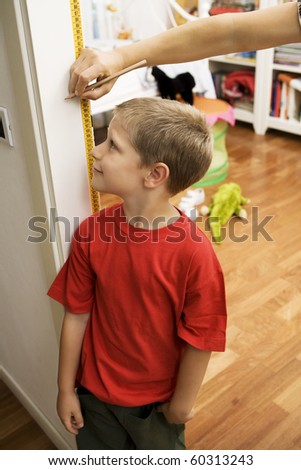 Portrait of young boy getting height measurement in doorway
