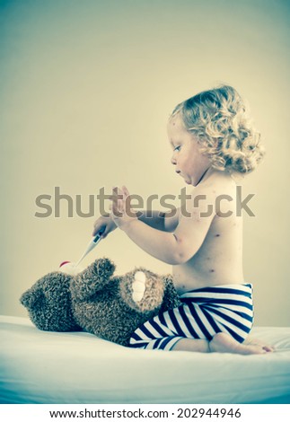 Sick girl is sitting on the bed with teddy-bear