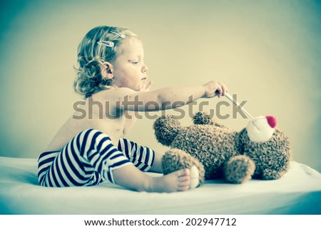 Sick girl is sitting on the bed with teddy-bear