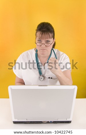 Nurse in front of a computer shaking fist.