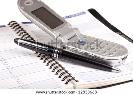 Old cell phone and pen sitting on a address book
