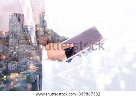 Double exposure of a businessman and a city using a tablet