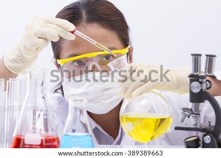 Focused young life science professional pipetting solution into the glass cuvette. Lens focus on the researcher\'s eye.