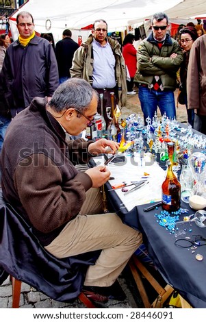 ISTANBUL - MARCH 29: A glass craftsman displays the art of making glassware at Ortakoy street market March 29, 2009 in Istanbul. Street peddlers sell various kind of home made items here.