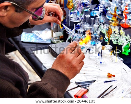 ISTANBUL - MARCH 29: A glass craftsman displays the art of making glassware at Ortakoy street market March 29, 2009 in Istanbul. Street peddlers sell various kind of home made items here.