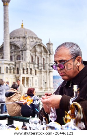 ISTANBUL - MARCH 29: A glassblower demonstrates the art of making glassware at Ortakoy street market March 29, 2009 in Istanbul. Street peddlers sell various kind of home made items here.