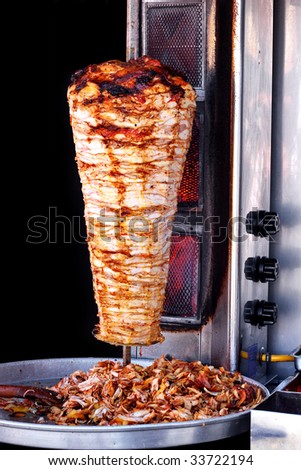 Doner kebab on it\'s special bbq set with tray of sliced meat seen from above