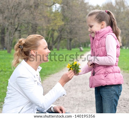 Daughter giving flowers to her mother in the park