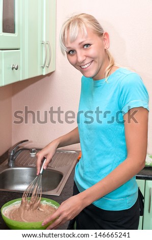 girl makes the food in the kitchen, using a mixer